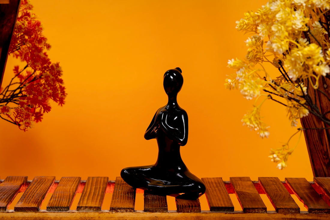 a black buddha statue sitting on a wooden table