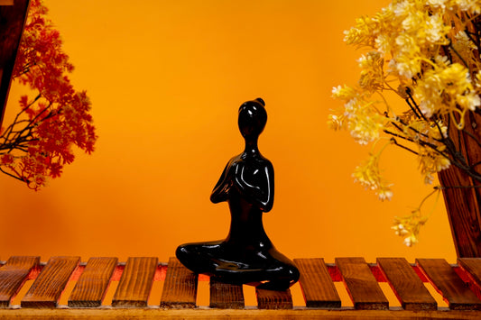 a black buddha statue sitting on a wooden table