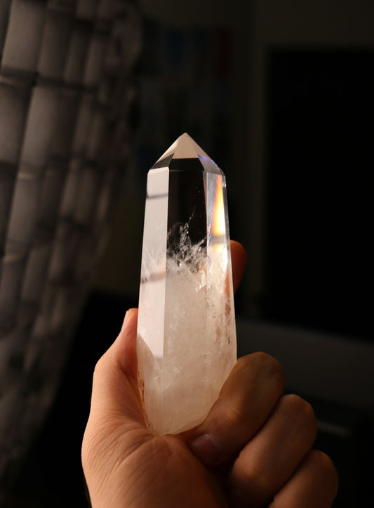 Hand holding a clear quartz crystal point